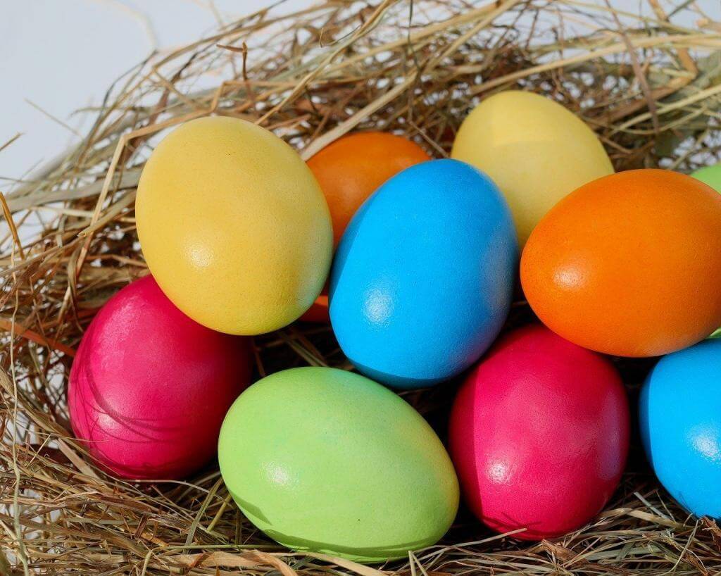 Bunt gefärbte Ostereier in verschiedenen Farben liegen in einem Nest aus Stroh