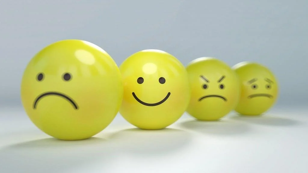 Vier gelbe Smiley-Bälle mit unterschiedlichen Gefühlsausdrücken wie traurig, fröhlich und wütend